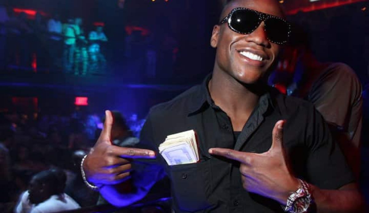 Floyd Mayweather Jr. pointing at cash in his front pocket