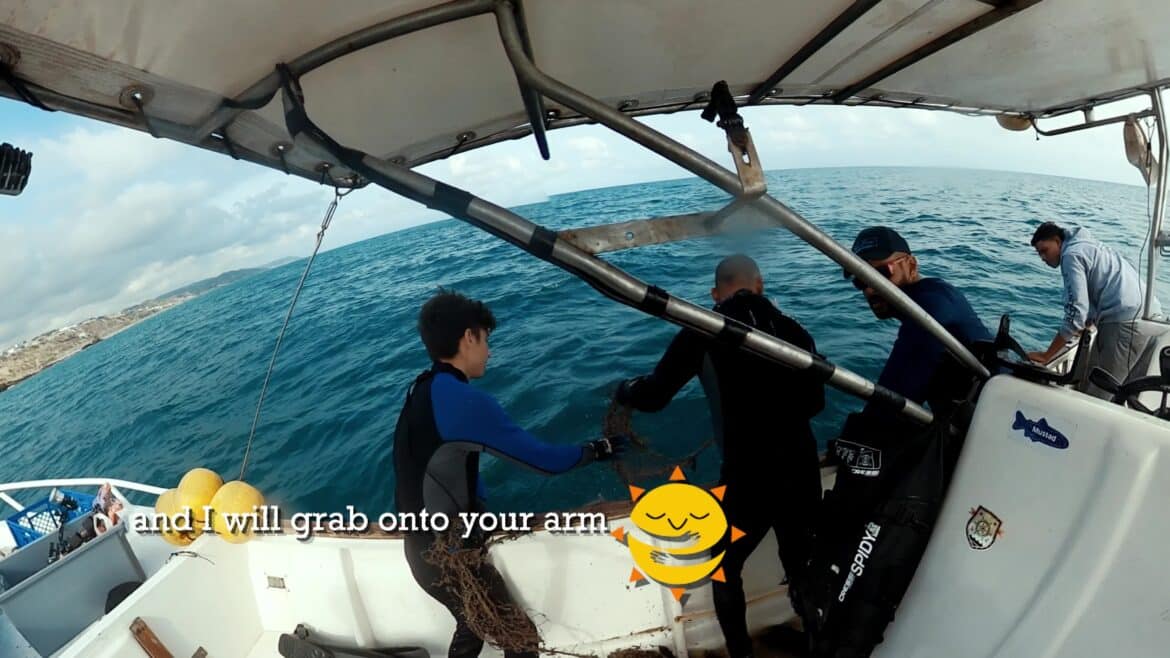 Divers hauling a recovered fishing net onto a boat near Manta, Ecuador