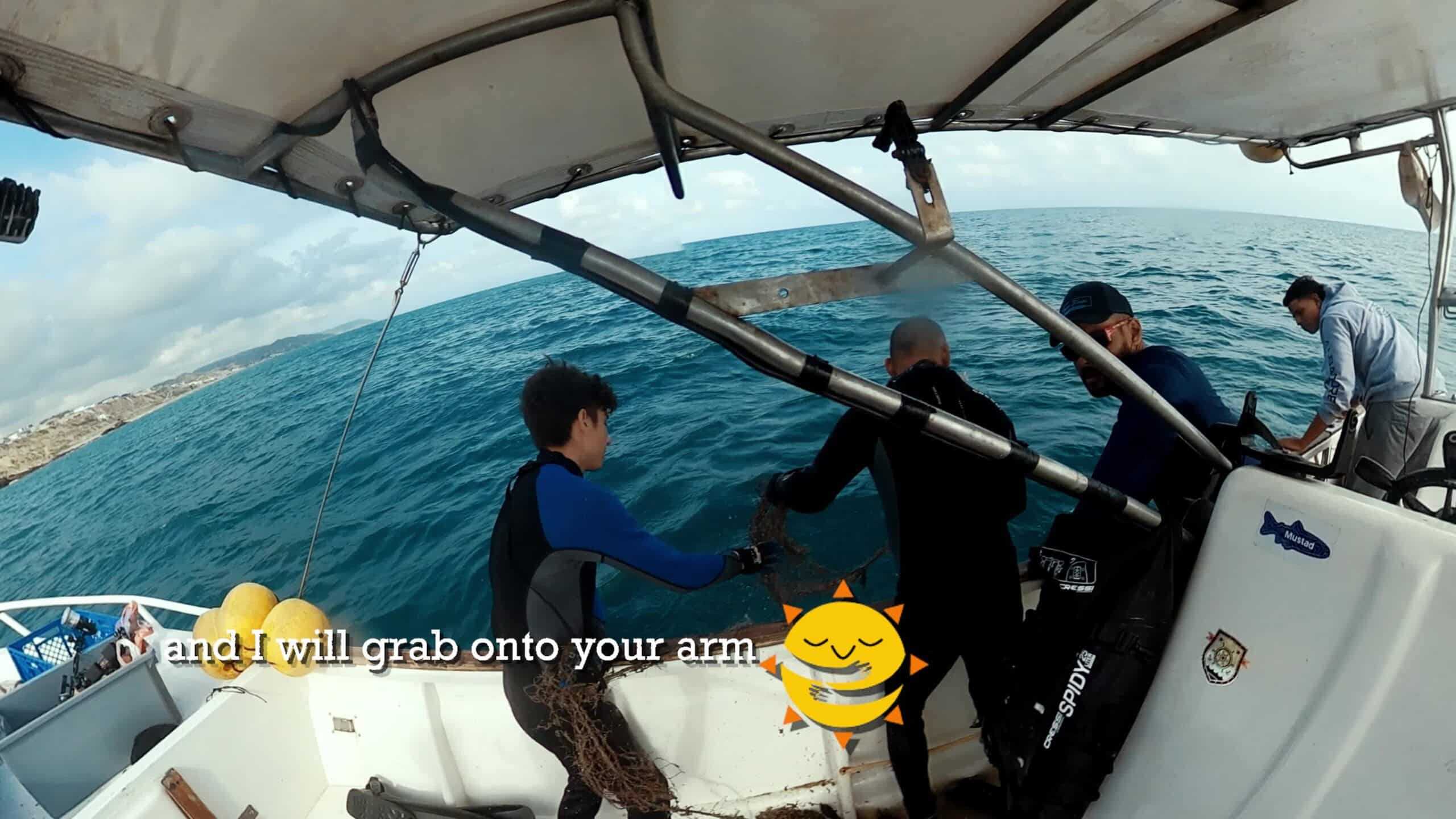 Divers hauling a recovered fishing net onto a boat near Manta, Ecuador